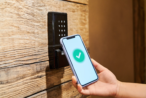 Human hand holding a mobile phone to open the automatic induction lock of the door