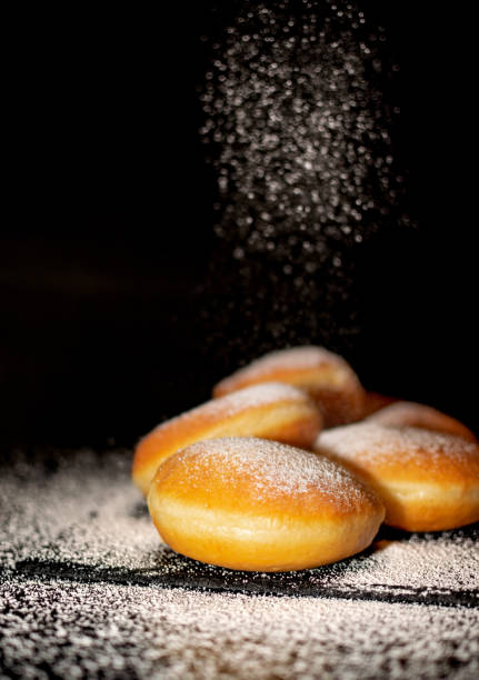 istock German Krapfen with drizzling glazed sprinkles in black elegant background 1661810248