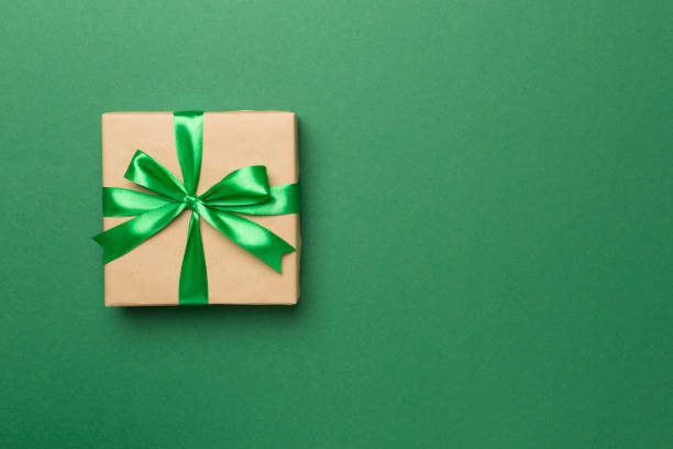 istock Gift box with green ribbon bow on color background, top view 1661818353