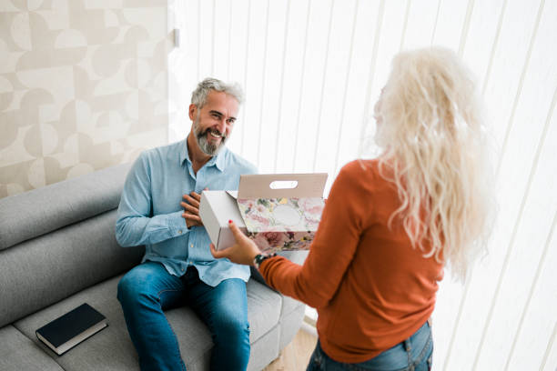 istock Woman at home surprising her husband with a gift 1661819485