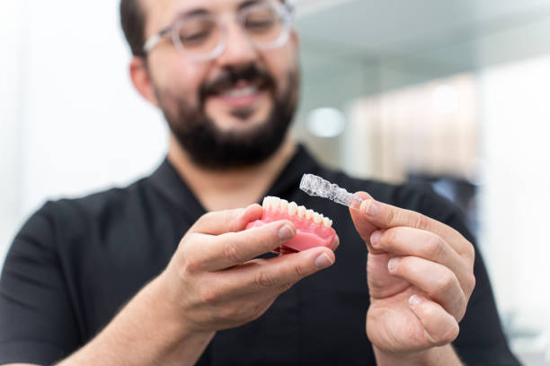 istock Dentist showing clear aligners on artificial human jaw presenting innovative teeth correction 1661858258