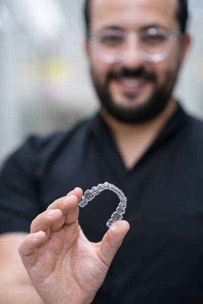 istock Skilled dentist with glasses showing clear aligners for professional teeth correction in clinic 1661858384