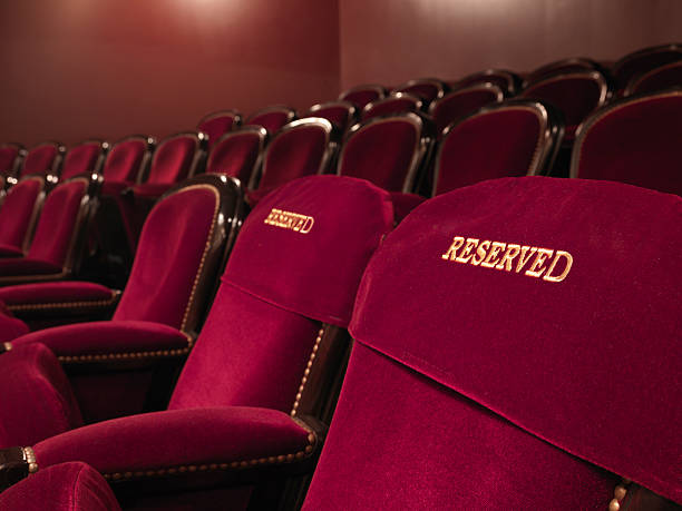 reserved theater seats two red reserved theater seats side by side in the middle of others reserved stock pictures, royalty-free photos & images