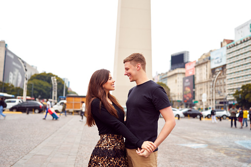 portrait happy young heterosexual couple hugging at the Obelisk in Buenos Aires