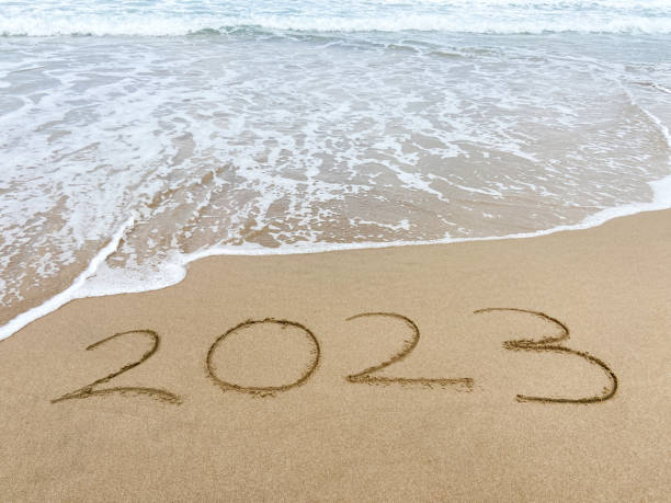 istock 2023 ends. 2023 on sand with sea wave at the beach 1661884093