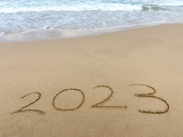 istock 2023 ends. 2023 on sand with sea wave at the beach 1661884630