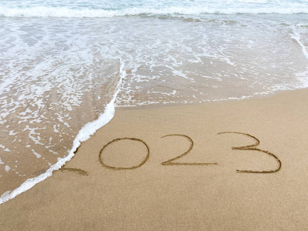 istock 2023 ends. 2023 on sand with sea wave at the beach 1661885177