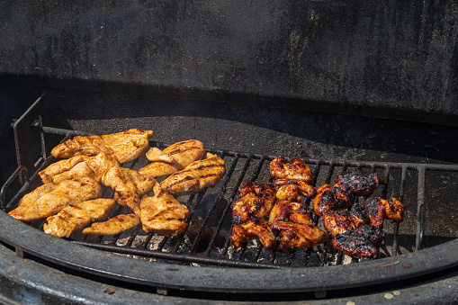 Chicken breasts and chicken wings are marinated and grilled on an outdoor grill.