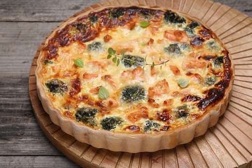 Pieces of delicious homemade quiche with salmon and broccoli on wooden board