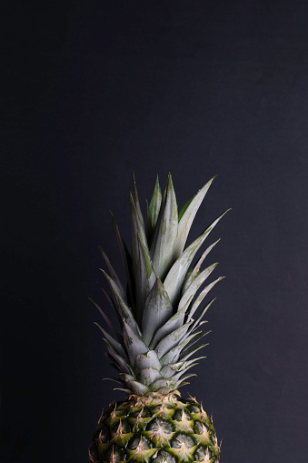 Part of single pineapple on black background.