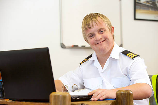 portrait of young pilot with down syndrome at desk. - downs syndrome work bildbanksfoton och bilder