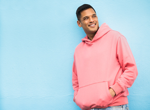 Happy, casual and man in studio thinking, relax and normal against a blue background space. Laugh, contemplation and  chilling Mexican man standing against mockup, real and cheerful while isolated