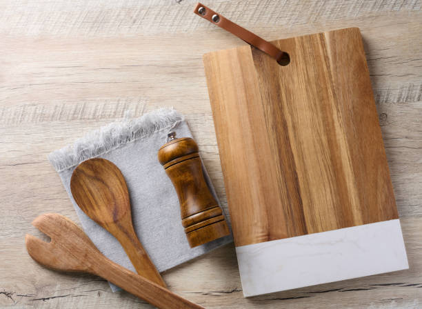 istock Empty rectangular wooden kitchen cutting board, empty bowl and wooden spoons on wooden table, top view 1661990618