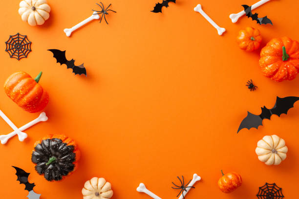 Festive Halloween party vision. Top-down image featuring pumpkins, paper bats, spiders, and Halloween-themed adornments on orange isolated backdrop. A great choice for text or advertising placement