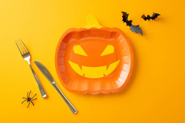istock Transform your Halloween party with this top view table arrangement. Featuring imaginative jack-o'-lantern plate, and cutlery. Creepy additions like spider and bats on orange background 1662003027