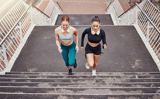 Fitness, sports or friends running on steps exercise together for healthy lifestyle, wellness or exercising for marathon. Athletes, runners or fast women training in cardio workout on stairs in city