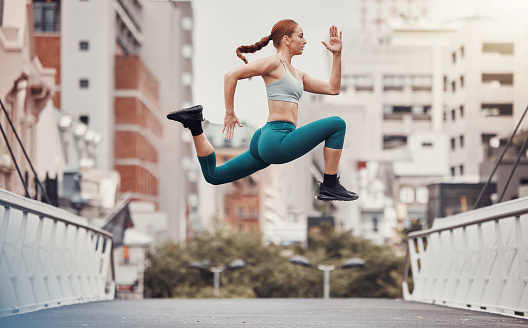Workout, jump and health with woman in city for training, cardio and endurance. Energy, fitness and exercise with girl athlete and warm up in urban town for sports, running and body wellness