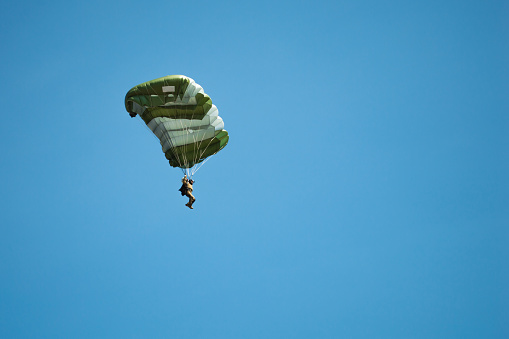 Man flying in the sky on a parachute. Skydiver with green parachute. Active sport concept
