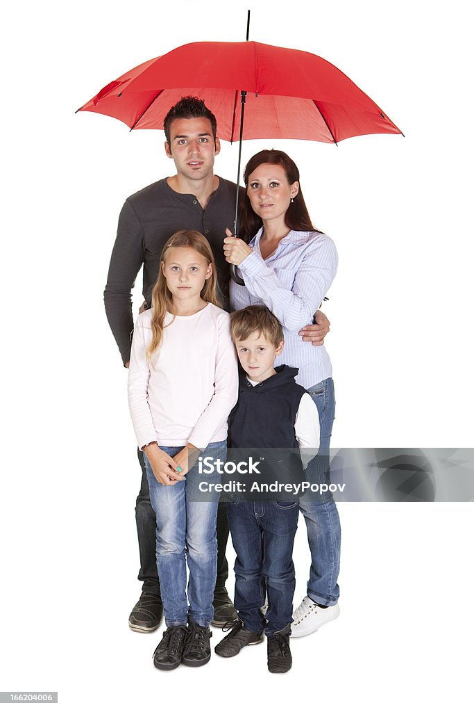 Felice giovane famiglia in piedi sotto un ombrello - Foto stock royalty-free di Ombrello