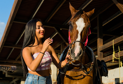 young woman smiling while playing with her horse outdoors