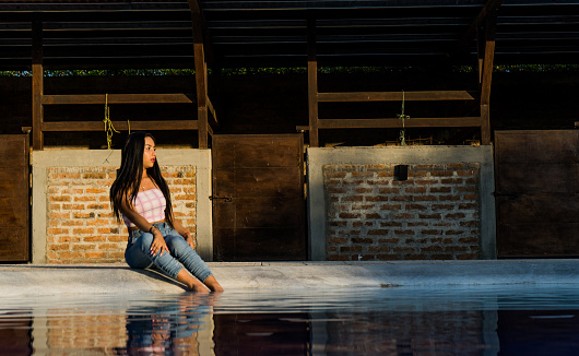 young woman sitting by a pool with her feet in it and a feeling of relaxation.