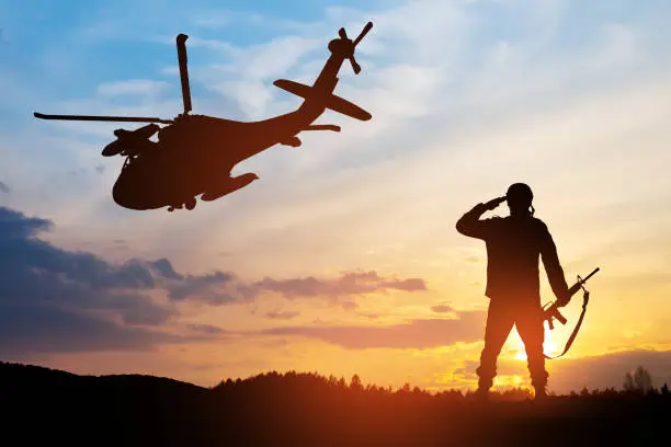 Silhouettes of helicopter and soldier on background of sunset. Greeting card for Veterans Day, Memorial Day, Air Force Day. USA celebration.