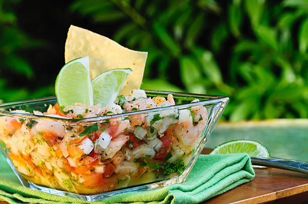 Ceviche in a bowl with lime on a wooden table stock photo