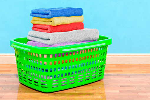 High angle view of blue towels in a laundry basket isolated on white background. Plastic bottles of laundry detergent and fabric softener complete the composition. High resolution 42Mp studio digital capture taken with Sony A7rII and Sony FE 90mm f2.8 macro G OSS lens