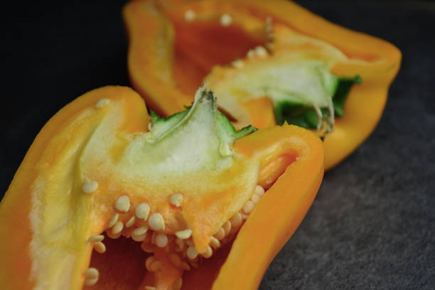two halves of a pepper lie on a black table