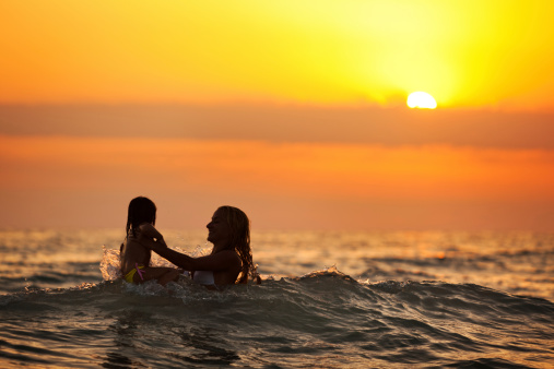 Mother play with little girl by the sea.