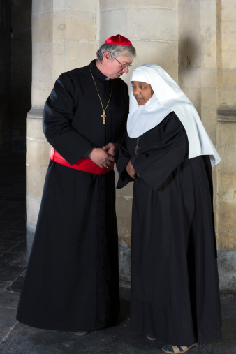 Nun and Cardinal talking against a background of an old pillar in a medieval church