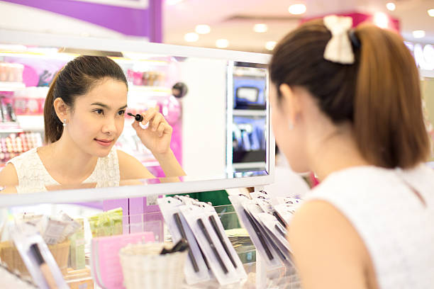 mulher asiática de compras na loja de produtos cosméticos. - asian ethnicity women shopping mall perfume - fotografias e filmes do acervo