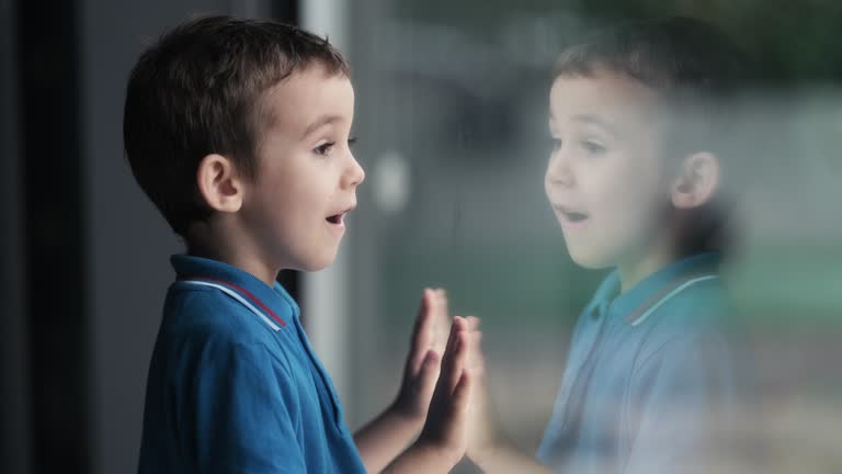 Little curious child boy looking out of window