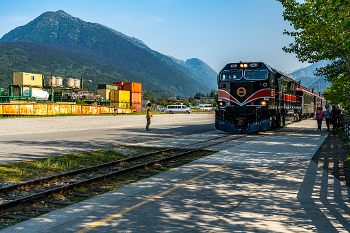 Skagway, Alaska - July 30, 2023: Tourists prepare to board the tourtrain for White Pass Summit excursion. Skagway townscape and White Pass & Yukon Route Railway in the morning, Alaska, USA.