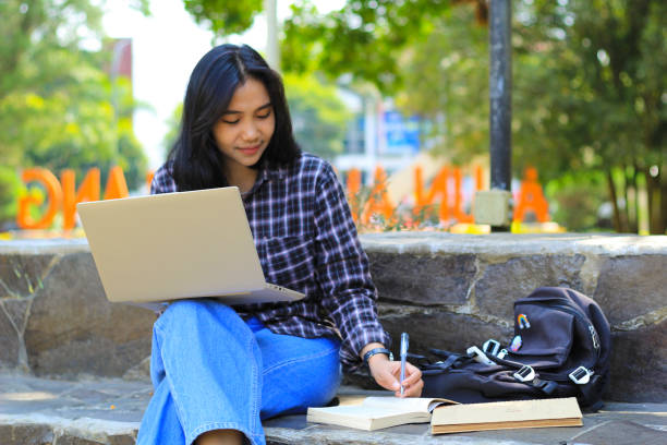 istock young smiling asian woman using laptop and writing notebook, cheerful asian student watching webinar and studying from e course 1662281121