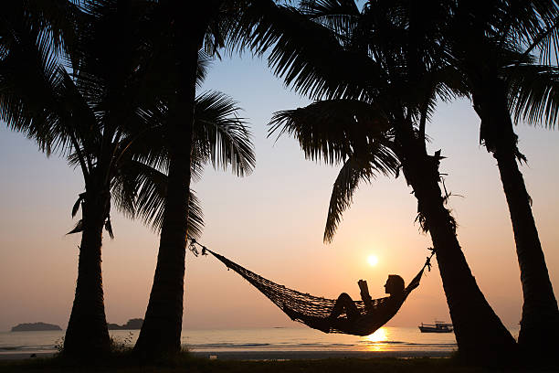 istock A person sitting in a hammock on the beach at sunset 166228959