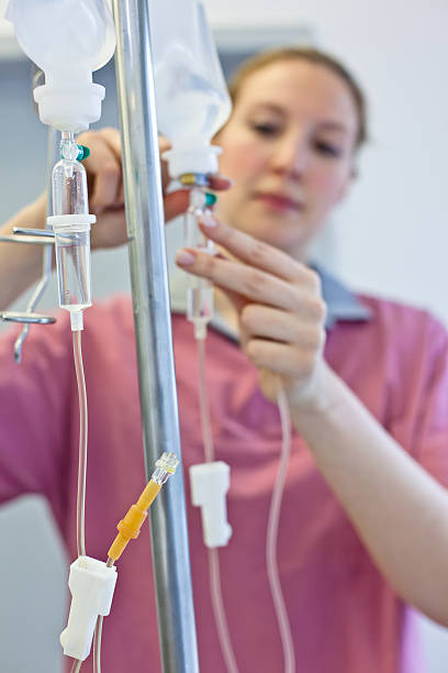 блондинка медсестра готовит собой капельница для внутривенного вливания - infused oil iv drip nurse hospital стоковые фото и изображения