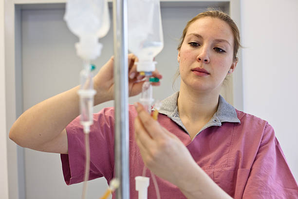 blondes weibliche krankenschwester vorbereitung einer infusion - kräuteröl stock-fotos und bilder
