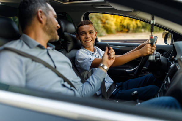 Father and teenage son geared up for a drive, sitting in the car with seatbelts fastened Father and teenage son geared up for a drive, sitting in the car with seatbelts fastened. teenager boy driving stock pictures, royalty-free photos & images