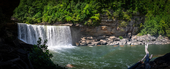 Panoramic view of Cumberland River waterfalls, with multiple paddle boats approaching the area where the cascading water creates splashes.