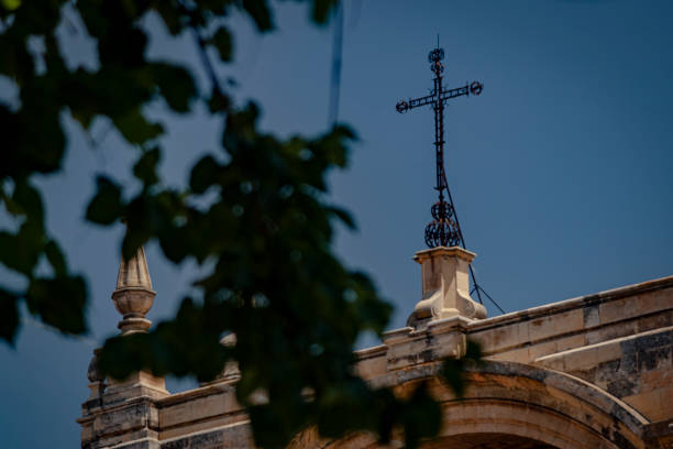 A cross on a church from the streets of Grenada behind a tree stock photo