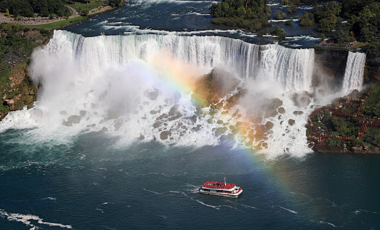 Aerial view of American and Bridal Veil Falls including the rainbow and Hornblower Boat sailing on Niagara River, Canada and USA natural border