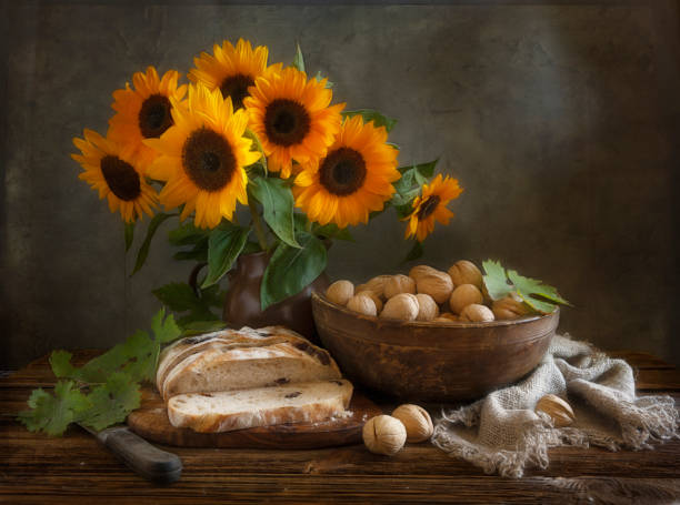 istock Homemade bread, walnuts, sunflowers and vintage ceramic kitchenware on an old wooden table. Artistic Still Life in Vintage Style. 1662411034