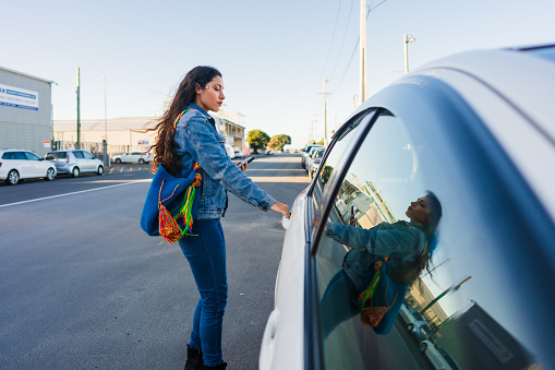 Woman on the road opening the door of the car ready to take a ride to home.