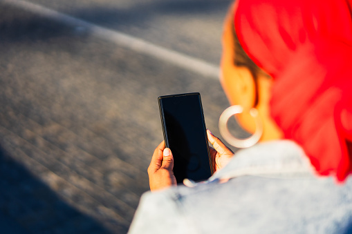 Over the shoulder view of a woman using smart phone with a blank screen, unrecognizable person.