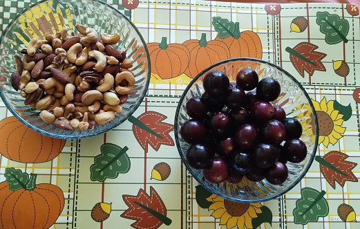 A bowl of muscadine grapes and a bowl of mixed nuts.