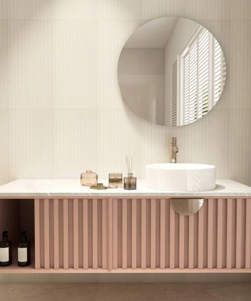istock Reed stick diffuser, white round washbasin on marble vanity countertop, pink corrugated counter, round mirror in cream wainscot wall bathroom 1662509203