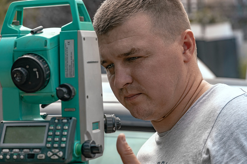 One surveyor worker works with equipment outdoors. A surveyor with a total station. A surveyor worker takes measurements in the field using a theodolite total station.