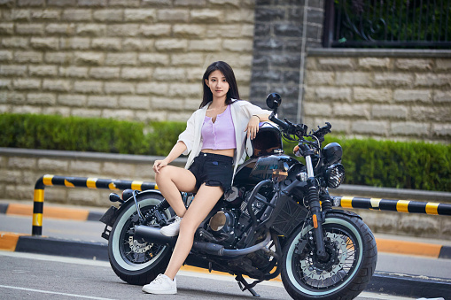 An Asian girl riding a motorcycle outdoors