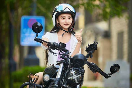 An Asian girl riding a motorcycle outdoors